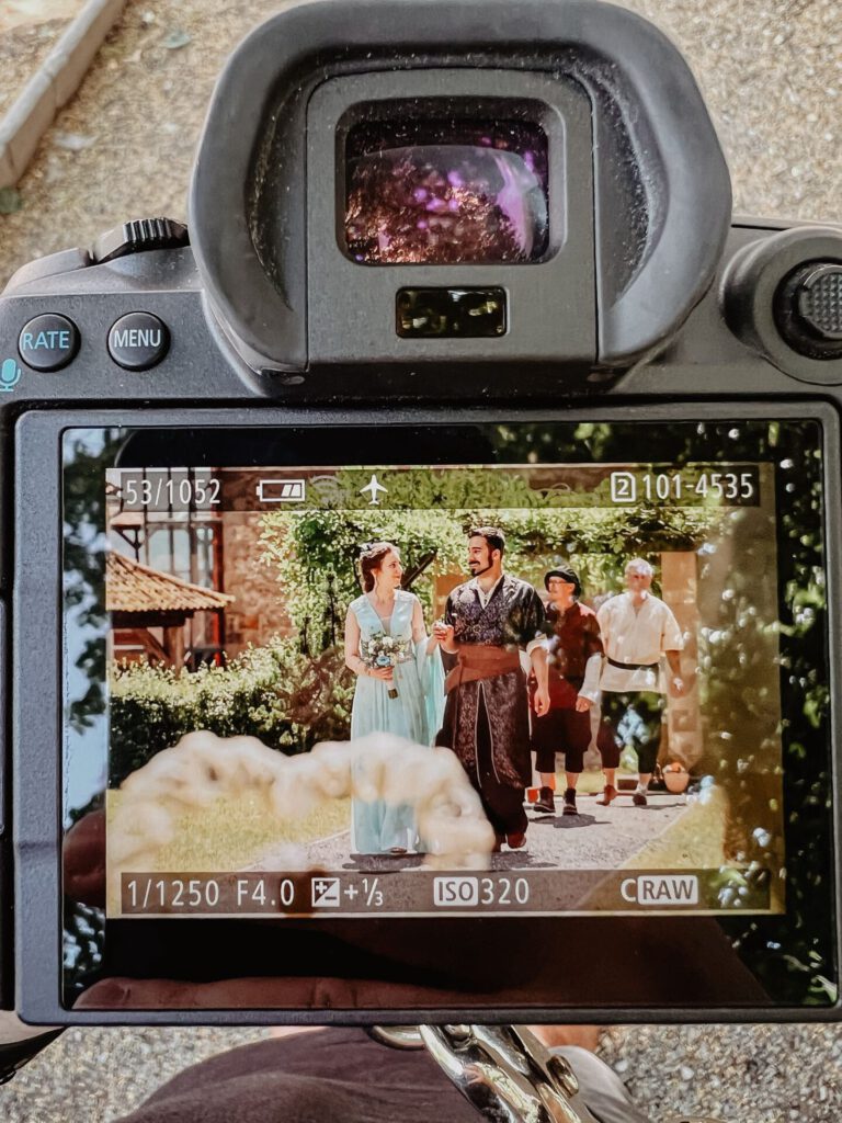 Blick durch die Kamera eines Hochzeitsfotografen – Brautpaar in traditioneller Kleidung beim Einzug