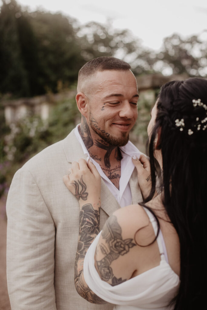 Bräutigam schaut lächelnd zur Braut im Schlosspark Altenstein