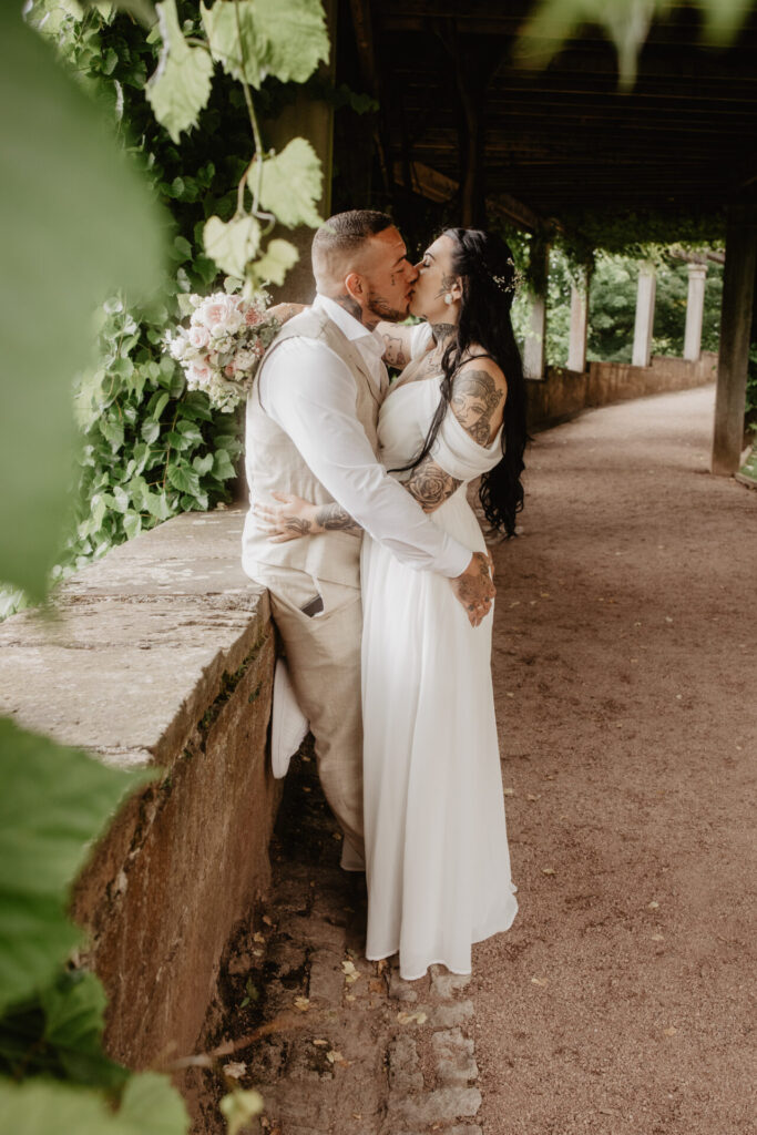 Brautpaar küsst sich unter einer Pergola im Schlosspark Altenstein
