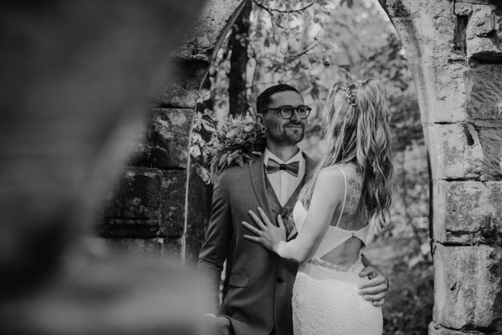 Brautpaar steht unter einem alten Steinbogen während eines Hochzeitsshootings in Eisenach
