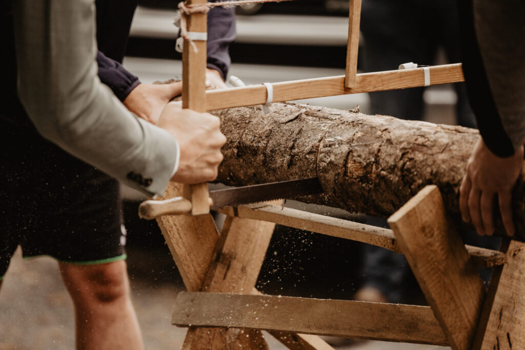 Brautpaar sägt gemeinsam einen Baumstamm bei einer Hochzeitstradition